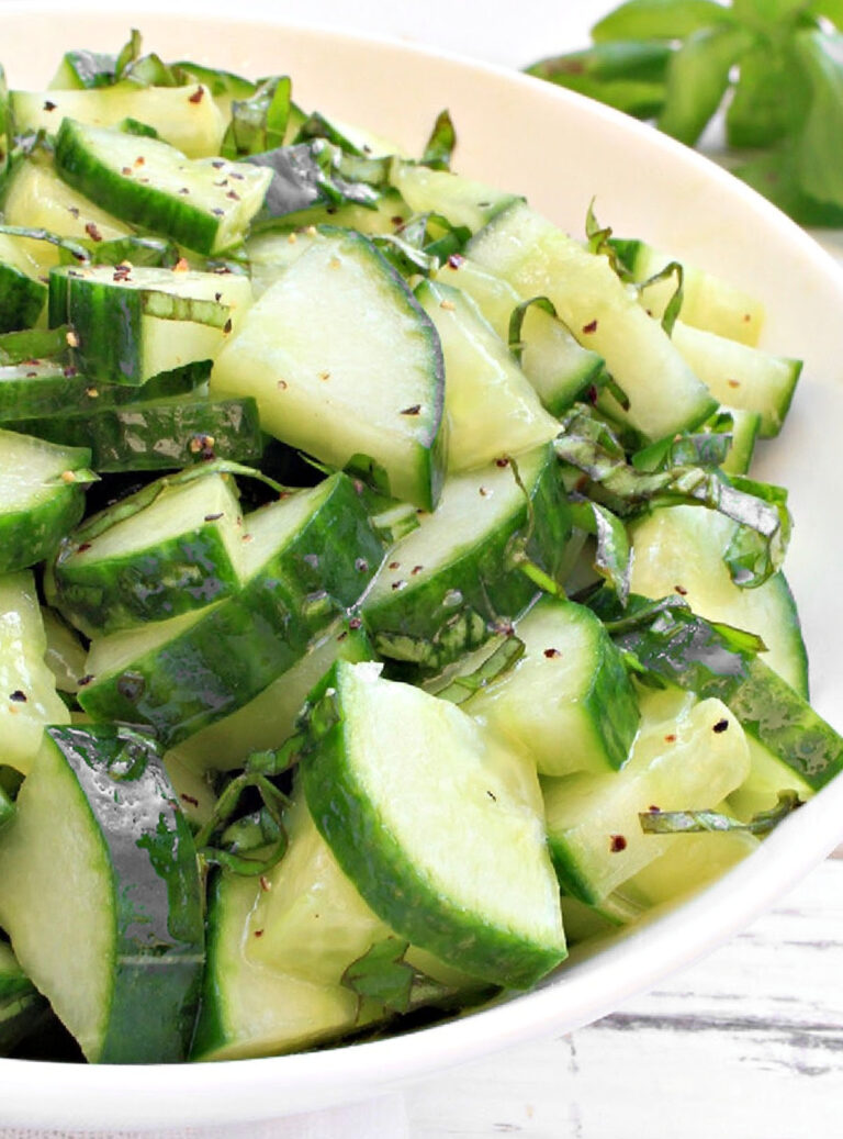 Bowl of cucumber salad with fresh basil ribbons and lemon dressing, served chilled.