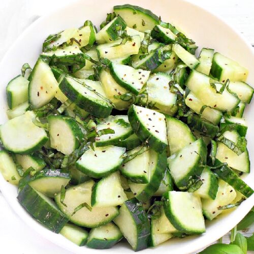 Bowl of cucumber salad with fresh basil ribbons and lemon dressing, served chilled.